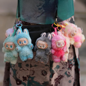 Sechs kleine PlĂĽschtiere in verschiedenen Farben an einer Handtasche angebracht