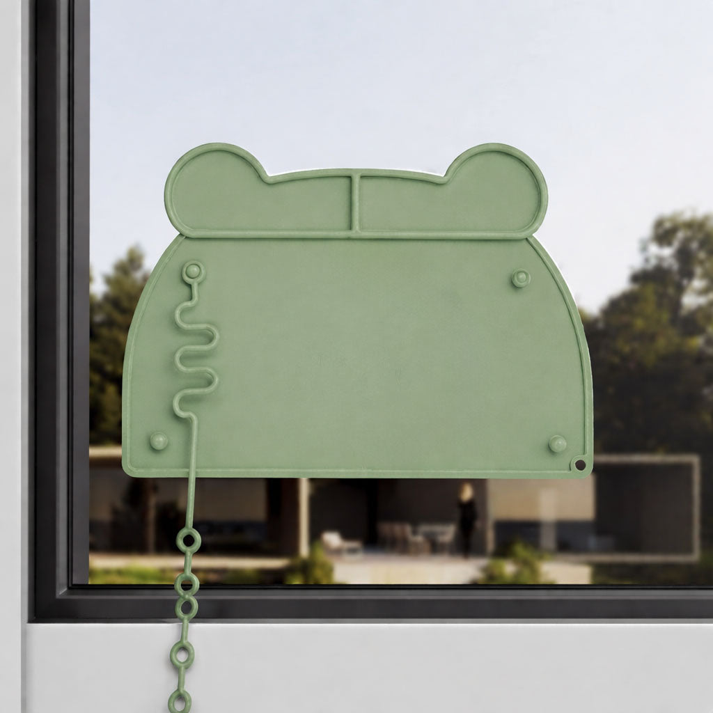 Grüne Silikonmatte in Bärenkopf-Form an einem Fenster befestigt
