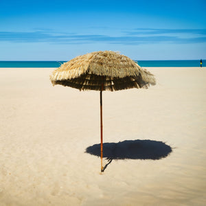 Parasol beige avec pied en bois de style hawaïen, dans un exemple d’utilisation sur une plage