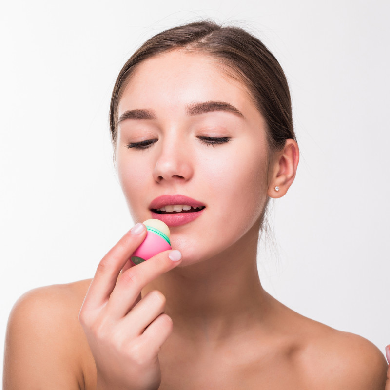 media/image/young-woman-applying-hygienic-lip-balm-on-white-wall.jpg